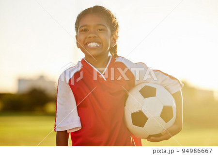 Young fitness girl, football or soccer player learning, training and exercise for healthy child development. Portrait of young happy sports kid on a field or stadium practicing for a game at sunset 94986667