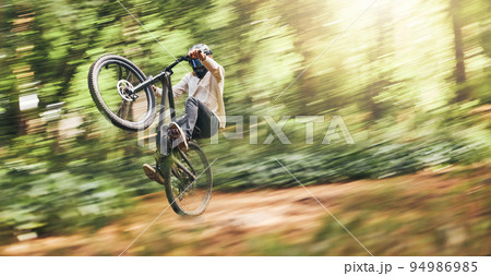 Motion blur of mountain bike man, action jump and bicycle speed adventure, freedom and fast race in woods. Cycling sports athlete training, moving and energy in forest, nature and outdoor competition Motion blur of mountain bike man, action jump and bicycle speed adventure, freedom and fast race in woods. Cycling sports athlete training, moving and energy in forest, nature and outdoor competition 94986985