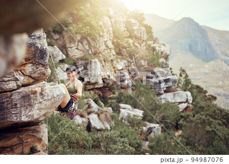 Mountain, rock climbing and sport with a sports woman and climber abseiling outdoor in nature. Fitness, exercise and health with a strong female athlete training or in a workout in the mountains Mountain, rock climbing and sport with a sports woman and climber abseiling outdoor in nature. Fitness, exercise and health with a strong female athlete training or in a workout in the mountains 94987076