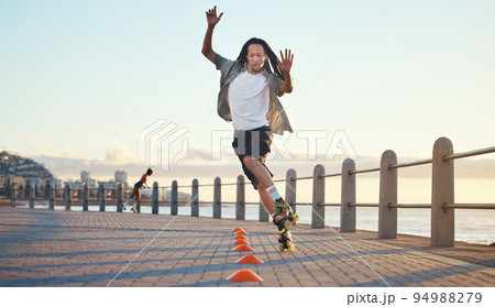Roller skating, man and fun sports by ocean, sea or beach in Florida in freedom exercise, workout drill and training at sunset. Fashion or cool local in wellness fitness skill in city park or street 94988279