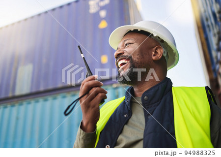 Logistics, supply chain and radio with a man delivery worker talking on a walkie talkie while working in a container yard. Ecommerce, stock and cargo in the retail, shipping and export industry Logistics, supply chain and radio with a man delivery worker talking on a walkie talkie while working in a container yard. Ecommerce, stock and cargo in the retail, shipping and export industry 94988325