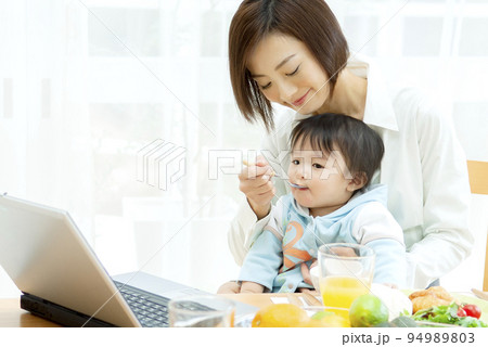 赤ちゃんにご飯を食べさせる母親 94989803