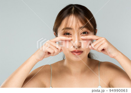 下瞼をおさえる女性 94990063