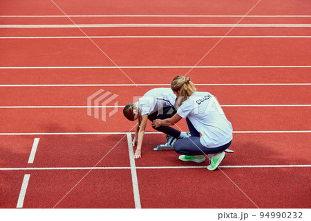 Female coach training athlete. Fit girl getting ready to run on treadmill at the stadium. Concept of sport, achievements, studying, goals, skills. Little teen girl training outdoor. 94990232