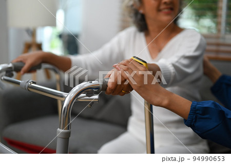 Close up view of caring nurse holding hands with a senior lady. Elderly healthcare and Home health care service concept 94990653