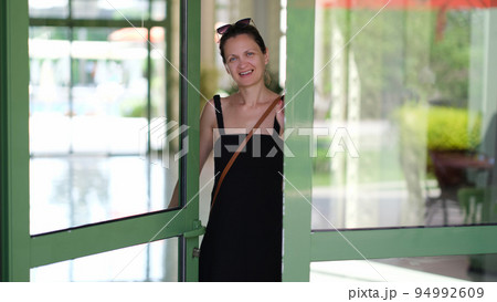 Smiling young woman opening front door to hotel house and shop 94992609