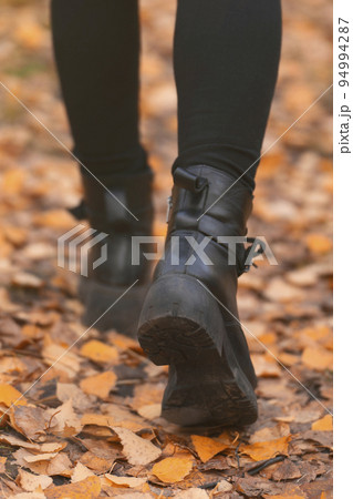 women's feet legs step. autumn walks in the park on orange foliage, healthy lifestyle 94994287