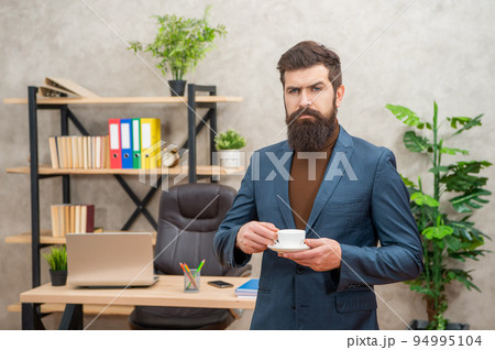 elegant bearded business man drinking coffee in the office with copy space, success 94995104