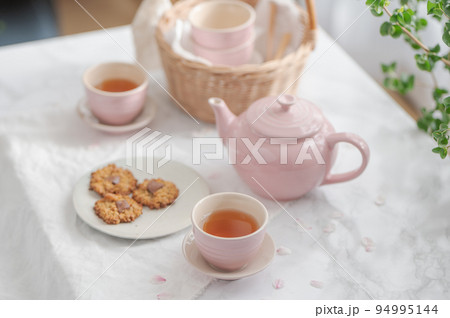 桜の花びらが散る中でティーカップに入った紅茶とクッキーでティータイム 桜の花びらが散る中でティーカップに入った紅茶とクッキーでティータイム 94995144