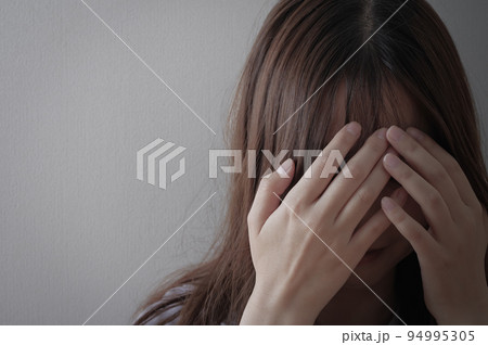 頭を抱える、辛そうな若い女性 94995305