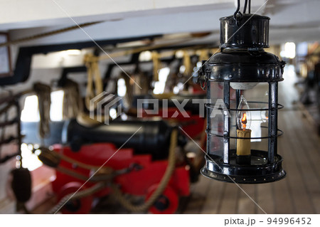 Historirical retro metal flashlight in front of cannon on battle sailing vessel 94996452
