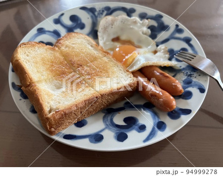 美味しそうな朝食のトーストと目玉焼きとソーセージ。モーニングセット 94999278