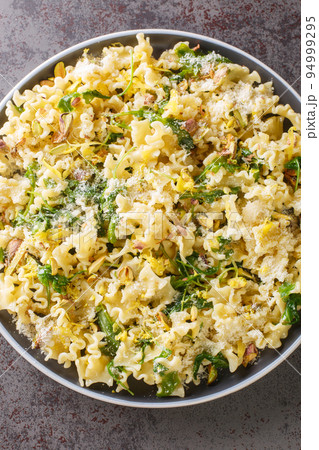 Sicilian Mafalda Corta Pasta di Gragnano with Lemon, Roasted Pistachios and Wild Rocket closeup in the plate. Vertical top view Sicilian Mafalda Corta Pasta di Gragnano with Lemon, Roasted Pistachios and Wild Rocket closeup in the plate. Vertical top view 94999295