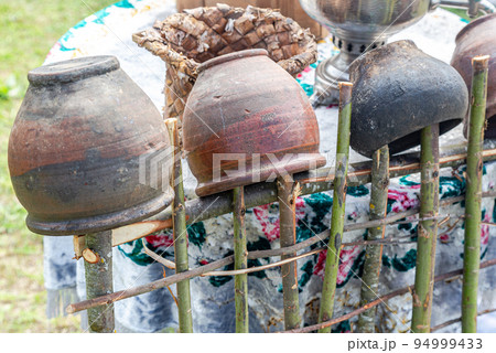 Vintage handmade ceramic pots hanging on a wooden hedge Vintage handmade ceramic pots hanging on a wooden hedge 94999433