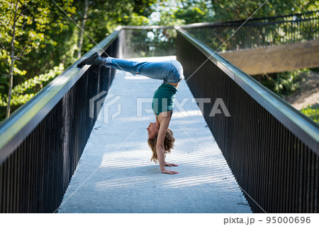 Athletic pose of an attractive 22 yo blonde girl on a pedestrian bridge 95000696