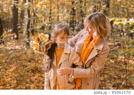 Beautiful lifestyle autumn photo mother and child walks evening in the park, warm sunlight. 95001570