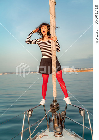 Woman standing on the nose of the yacht at a sunny summer day, breeze developing hair, beautiful sea on background Woman standing on the nose of the yacht at a sunny summer day, breeze developing hair, beautiful sea on background 95001718