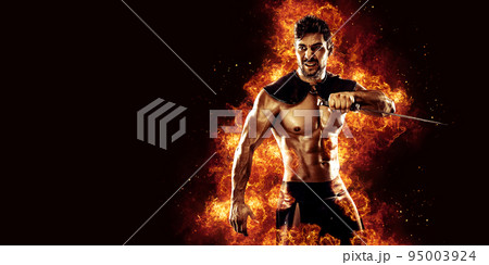 Sportive man in leather warrior costume with sword, fire on background 95003924
