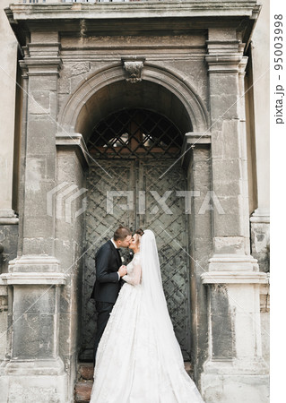 Lovely wedding couple kissing in the old city Lovely wedding couple kissing in the old city 95003998