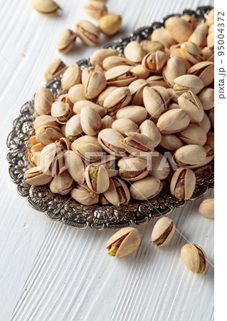 Salted pistachios on a white wooden table. Salted pistachios on a white wooden table. 95004372