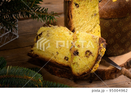 Piece of Traditional Italian Christmas Cake Panettone with green bow on wooden rustic background, close up 95004962