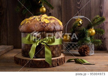 Traditional Italian Christmas Cake Panettone with green bow and festive decoration on wooden rustic background Traditional Italian Christmas Cake Panettone with green bow and festive decoration on wooden rustic background 95004973
