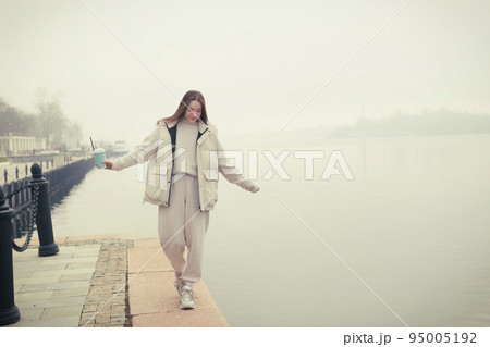 brunette girl with long hair in white jacket full body portrait on foggy landscape background 95005192
