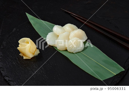 Fresh octopus sashimi on bamboo leaf on black. 95006331