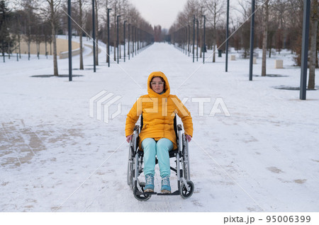 Woman in wheelchair relaxing in winter park. Woman in wheelchair relaxing in winter park. 95006399
