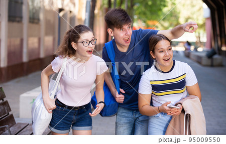 Happy teenagers strolling through city streets on summer day 95009550