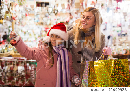 Happy mom and daughter choose christmas balls at street market 95009928