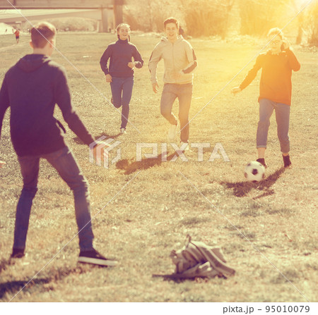 Cheerful teenagers are jogning with ball in park Cheerful teenagers are jogning with ball in park 95010079
