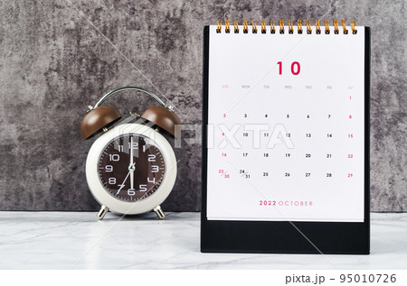 The October 2022 Monthly desk calendar for 2022 year and Alarm clock vintage background. 95010726