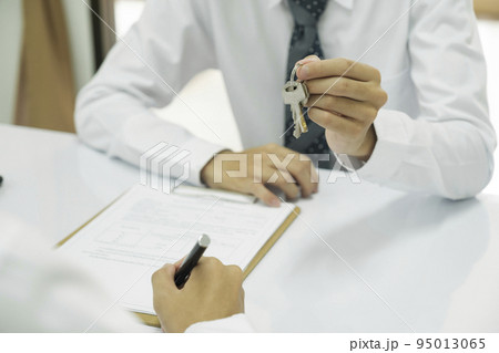 Real estate agent giving house keys to client after signing home loan contract. Real estate agent giving house keys to client after signing home loan contract. 95013065
