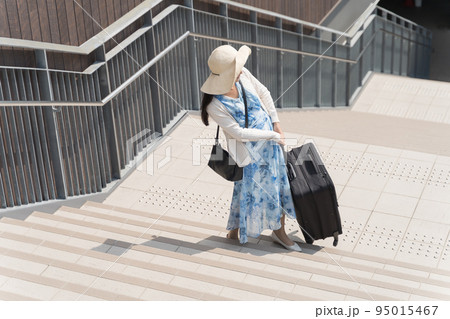 階段でスーツケースを引き上げる若い女性 階段でスーツケースを引き上げる若い女性 95015467