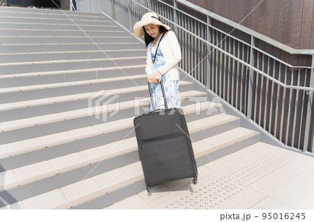 階段でスーツケースを引き上げる若い女性 階段でスーツケースを引き上げる若い女性 95016245