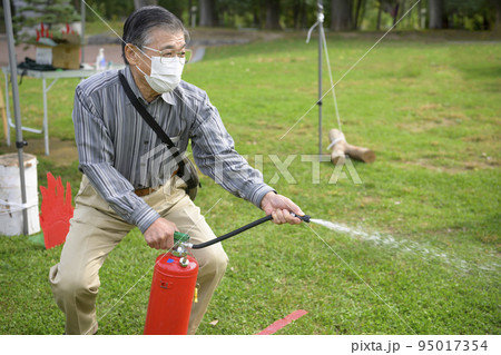 防災イベントで消化器を使う訓練に参加した男性 防災イベントで消化器を使う訓練に参加した男性 95017354