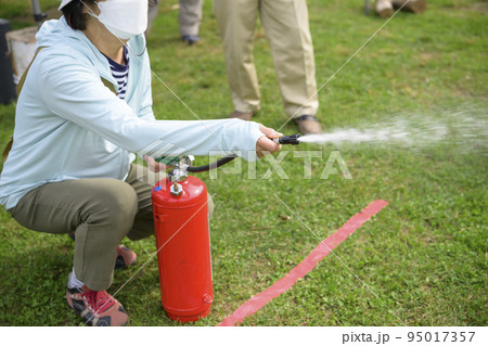防災イベントで消化器を使う訓練に参加した女性 防災イベントで消化器を使う訓練に参加した女性 95017357