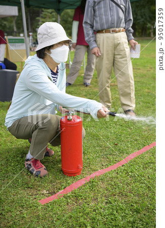 防災イベントで消化器を使う訓練に参加した女性 防災イベントで消化器を使う訓練に参加した女性 95017359