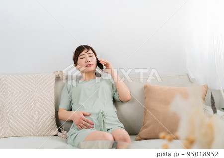 陣痛がきて電話するアジア人女性(腹痛・胃腸炎・食中毒) 陣痛がきて電話するアジア人女性(腹痛・胃腸炎・食中毒) 95018952