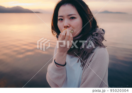 朝焼けが綺麗なパンを食べる女性の写真 朝焼けが綺麗なパンを食べる女性の写真 95020304