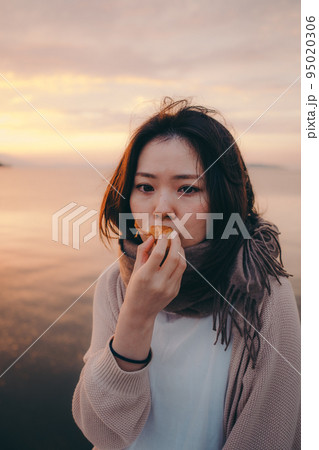 朝焼けが綺麗なパンを食べる女性の写真 朝焼けが綺麗なパンを食べる女性の写真 95020306