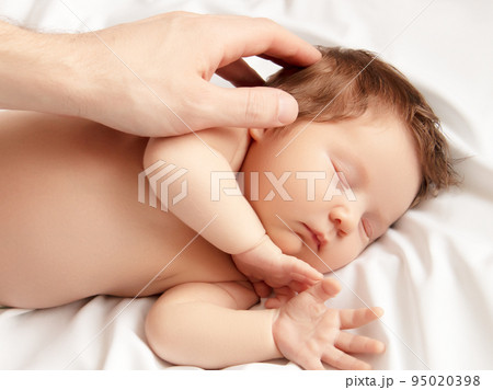 A newborn baby sleeps on a white blanket. Bright A newborn baby sleeps on a white blanket. Bright 95020398