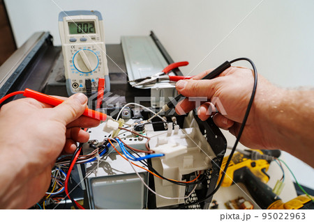 Diagnostics repair of microwave oven. hands of master with measuring instrument  95022963
