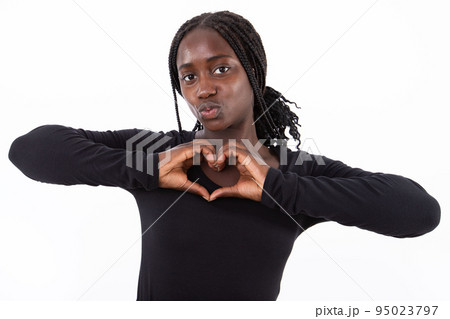 Portrait of young woman making heart gesture and pouting lips 95023797