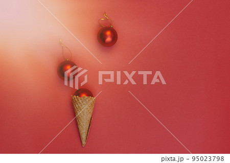 Soft selective focus Christmas balls decoration in waffle cone on red background under bright sun rays. Round toys with gold thread. Flat Lay 95023798