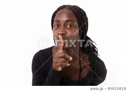 Portrait of happy young woman standing with finger on lips Portrait of happy young woman standing with finger on lips 95023819