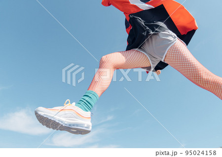 おしゃれなスポーツファッションでジャンプする女性 おしゃれなスポーツファッションでジャンプする女性 95024158