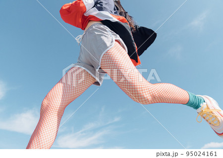 おしゃれなスポーツファッションでジャンプする女性 95024161