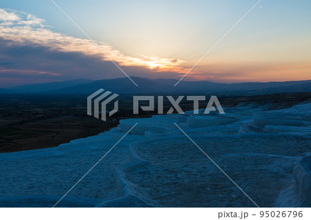 トルコ　ヒエラポリス・パムッカレの石灰棚と夕焼けでオレンジに染まった空 95026796